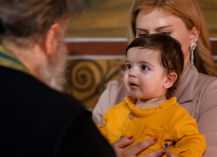 A touching family moment during an indoor church event, showing a child held by a parent.