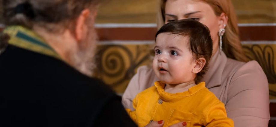 A touching family moment during an indoor church event, showing a child held by a parent.